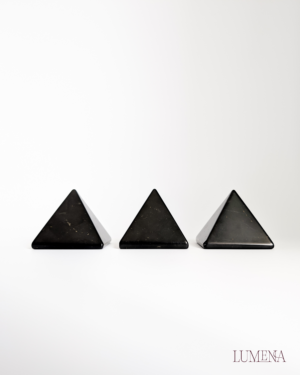 Image shows 3 black shungite pyramids all in a line, against a white backdrop.